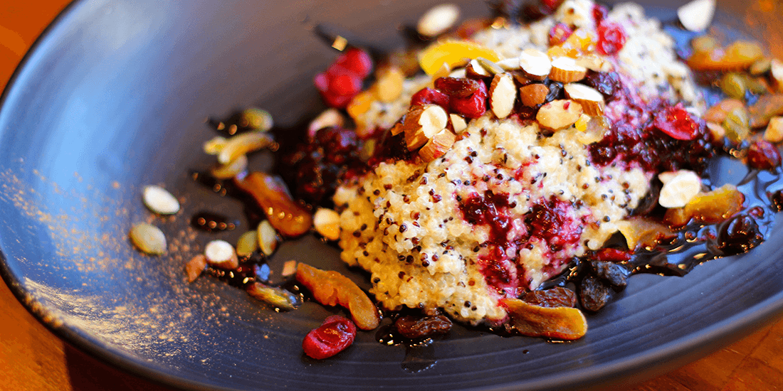 Quinoa porridge with roasted almonds, berry compote and maple syrup drizzle