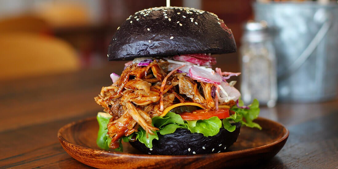 Bourbon pork burger with tangy apple slaw on a black brioche bun